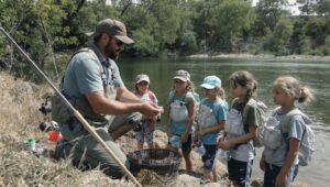 Niños de San José de Mayo aprendiendo pesca deportiva y respeto por la naturaleza junto al río.